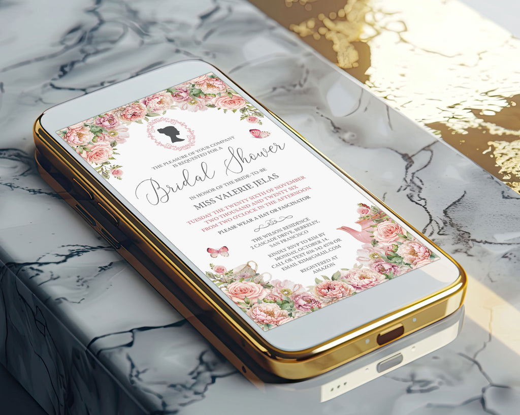 A gold mobile phone showing a pretty blush pink bridal shower victorian style invitation on the screen laying on a marble surface