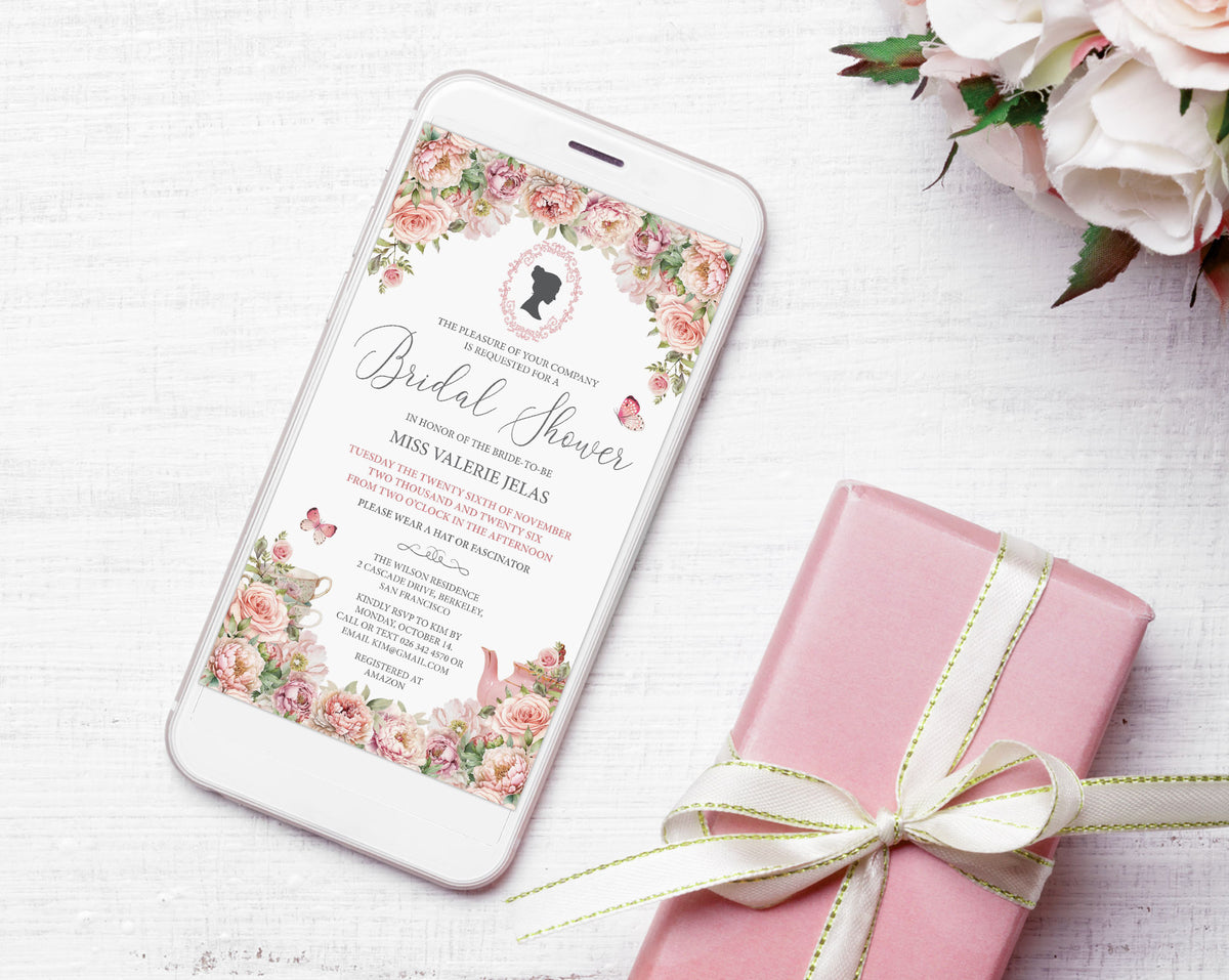 Pretty blush pink flower Bridal Shower Mobile invitation with Bridgerton Style cameo and butterflies showing on the screen of a white mobile phone, laying on a white background next to some white roses and a pink wrapped gift