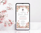 A smartphone mockup displaying a regency style blush pink floral bridal shower invitation design, surrounded by pink blossoms on a clean white background.