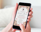 2 hands holding a black mobile phone showing a blush pink bridal shower invitation with a white background