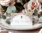 Floral name card on a decorative plate with pink roses in the background