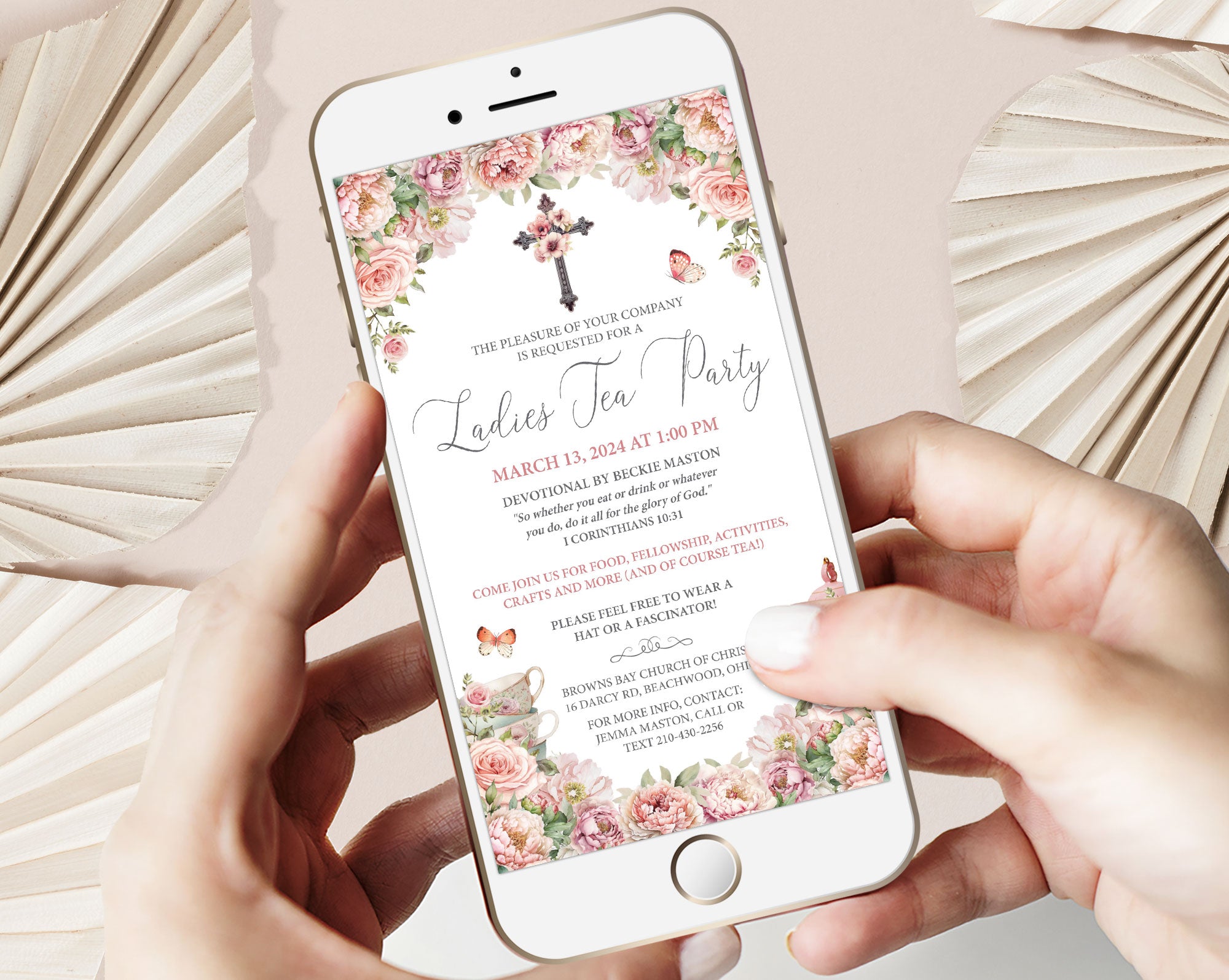 blush pink flower church event ladies tea invitation on a mobile phone held by two hands in front of beige dried leaves