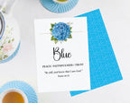 two 5 x 7 blue table cards with blue flower and scripture, laying on a white background, the 2nd card shows the blue pattern back and are surrounded by a tea set
