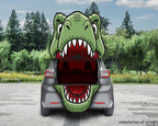 A gray hatchback car shown from the rear with its trunk open, featuring a large green cartoon dinosaur mouth graphic covering the trunk opening. The scene is set outdoors on a paved area with trees and grass in the background.