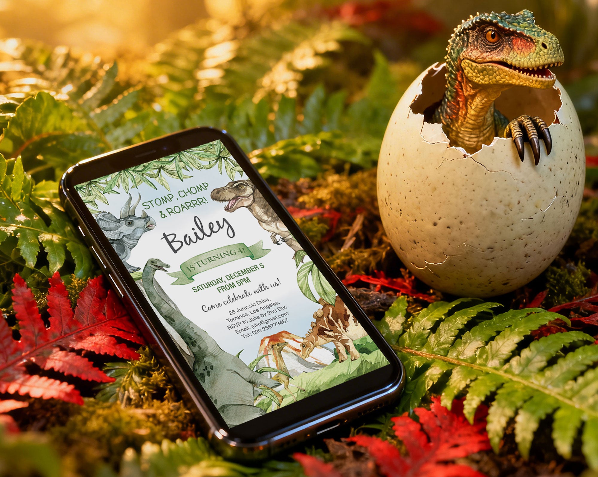 A black mobile phone with a Dinosaur Party Invitation showing on the screen, lying in a forest next to an egg with a dinosaur hatching out of it