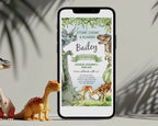 A boys dinosaur invitation showing on a screen of a mobile phone that is leaning on a grey wall with toy dinosaurs and leaves next to it