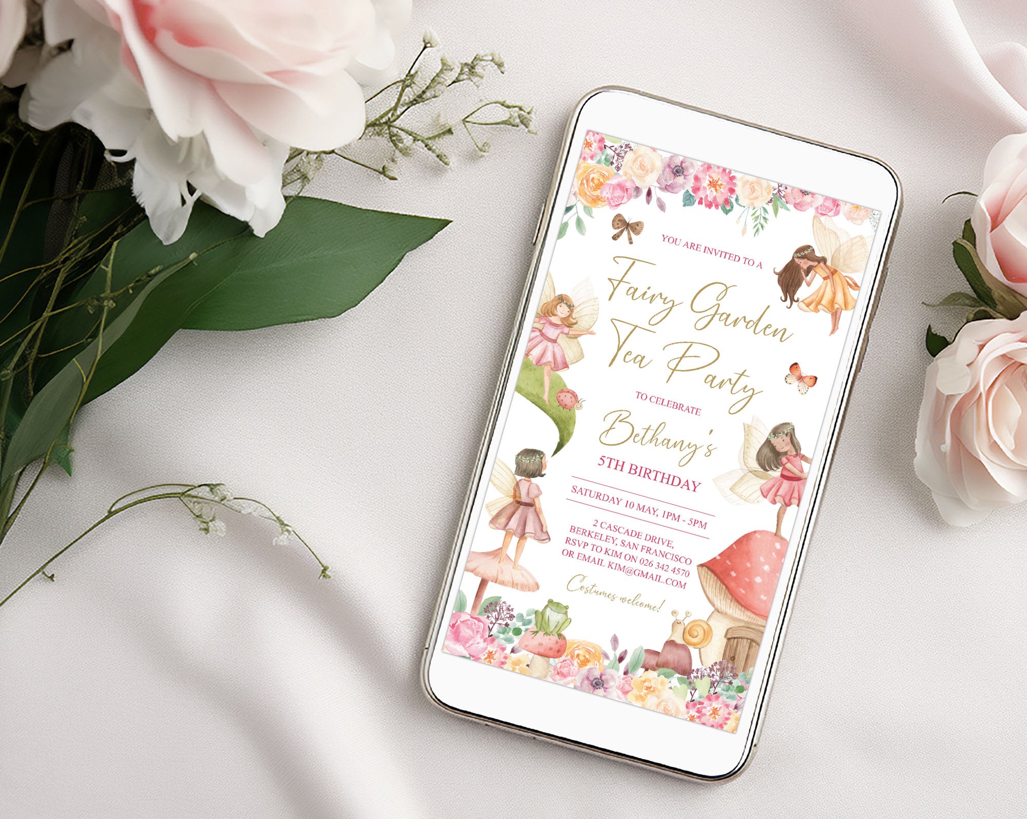 a smart phone laying on a white cloth background with a Fairy garden kids birthday invitation showing on the screen, next to some light pink roses