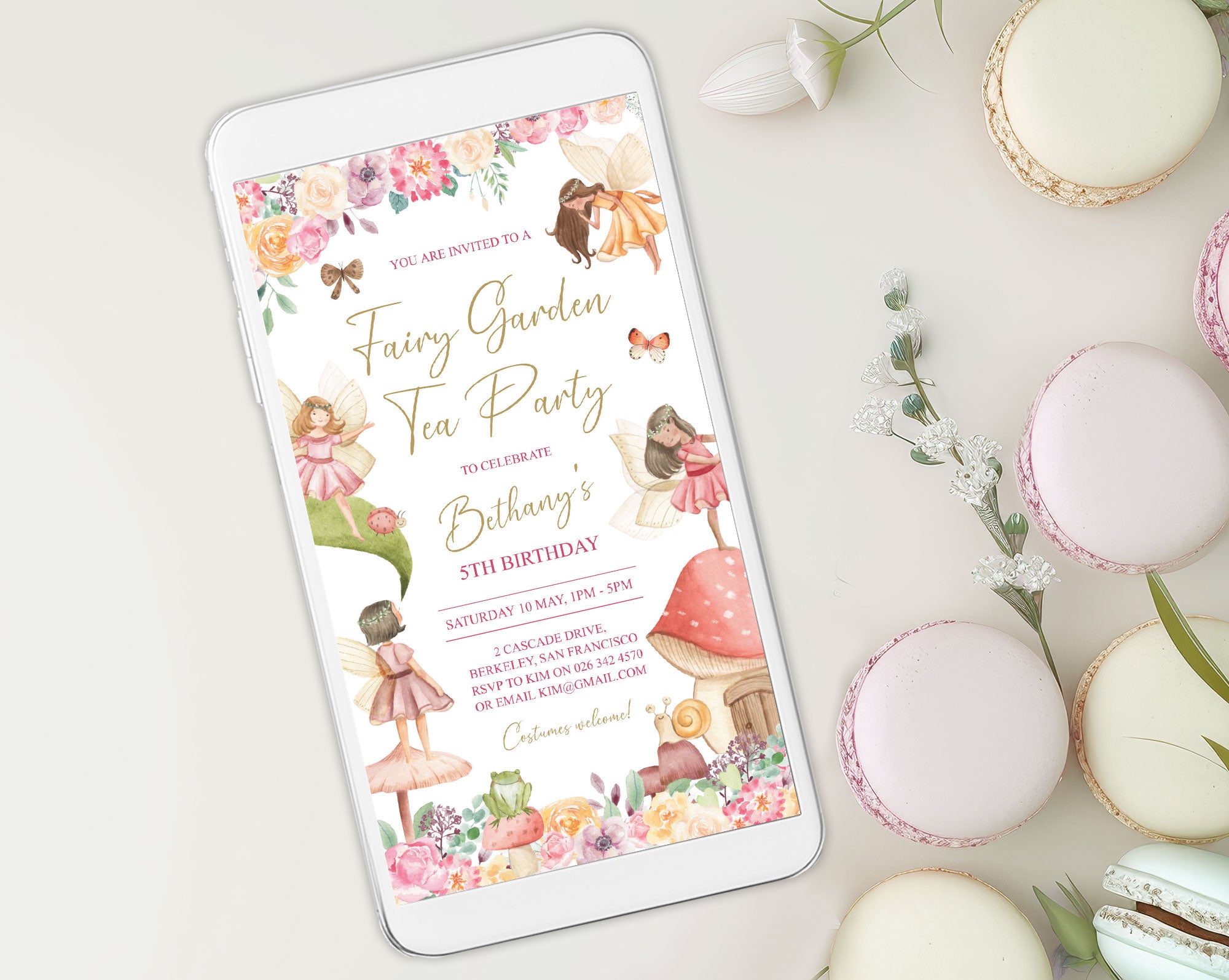 pretty pastel macarons laying next to a white mobile phone that is showing a fairy garden tea party