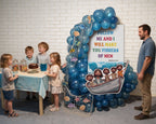 A children's party setup in a room with a white brick wall, featuring a large blue balloon arch decorated with fishing net, sea creatures, and a 'Follow Me and I Will Make You Fishers of Men' sign. Four children are gathered around a small table with a cake and drink, and a man in a blue shirt stands to the right.