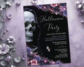A gothic Halloween party invitation card with a black background, white script text, a large skull illustration, and floral borders in purple, pink, and gray, styled on a lavender textured surface with paper flowers.