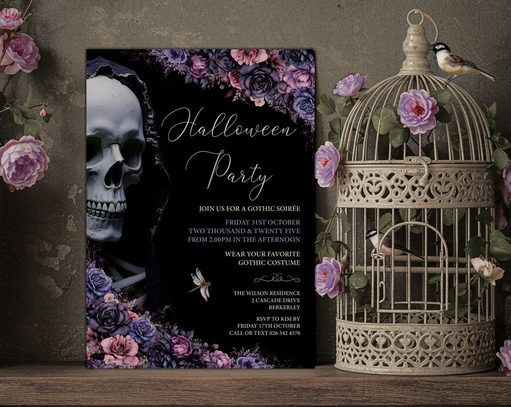 A gothic Halloween party invitation card displayed on a rustic wooden surface next to a vintage-style birdcage with birds perched on it. The invitation features a black background with a white skull, purple and pink roses, and elegant white script text reading 'Halloween Party'.