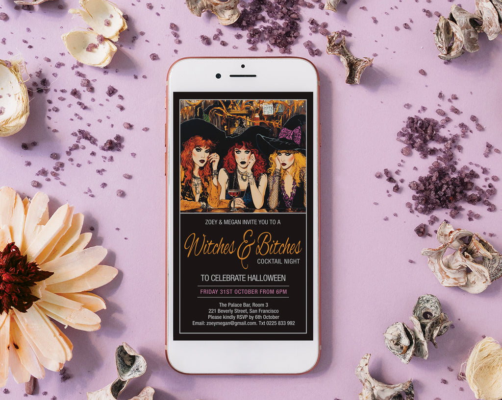 A white smartphone lying on a lavender flat-lay background, displaying a Halloween-themed invitation design with illustrated women in witch hats and gold script text. The phone is surrounded by dried flowers, small skull decorations, and scattered purple powder.