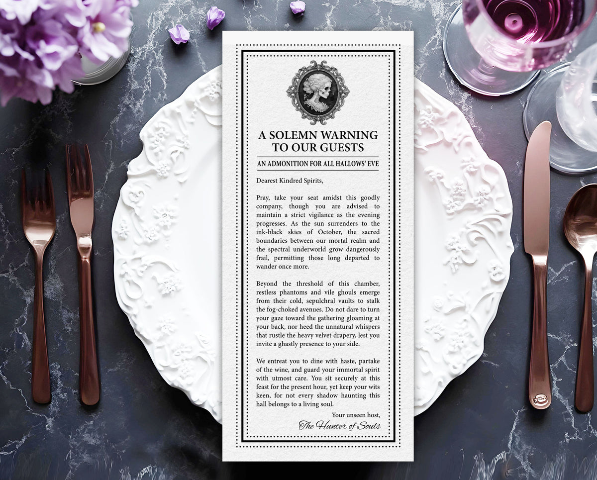 A printed Halloween Victorian style card with creepy skull cameo reading 'A SOLEMN WARNING TO OUR GUESTS' is laid flat on a dark marble surface, surrounded by white plates, silverware, a glass of red wine, and purple flowers.