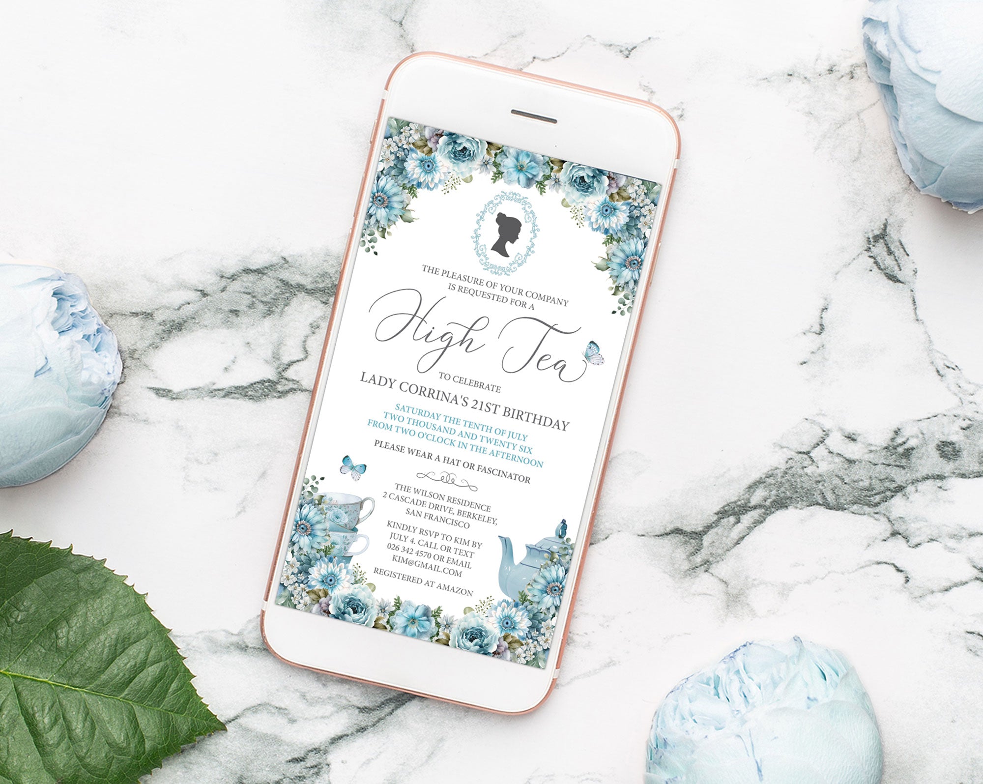 Phone displaying a high tea invitation on a marble gold rimmed mobile with a dusty blue afternoon tea invitation displaying on it surface with decorative flowers and a leaf.