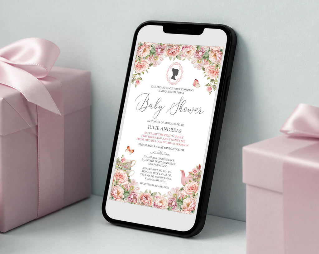 a black mobile phone showing a pink flower baby shower regency style invitation leaning up against a white wall next to some pink wrapped gifts