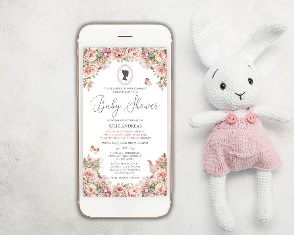 a blush pink baby shower invitation showing on the screen of a white mobile phone, laying on a white background next to a stuffed rabbit with pink dungarees