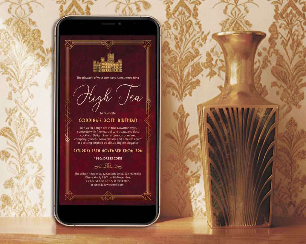 a black mobile phone with a downton birthday invitation showing on the screen leaning up again a gold patterned wall next to an art deco gold vase