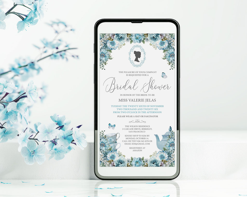 A smartphone mockup displays a dusty blue flower regency style bridal shower invitation. The phone is shown standing upright on a white surface with decorative blue blossoms in the background.