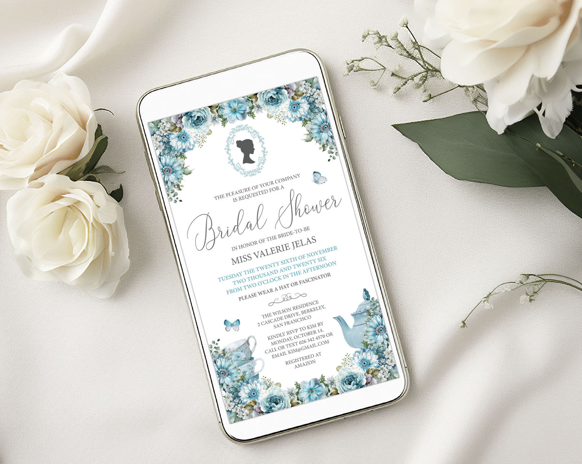 A smartphone displaying a bridal shower invitation design with blue floral borders, butterflies, and a blue teapot, styled on a white fabric surface with white roses and green leaves.