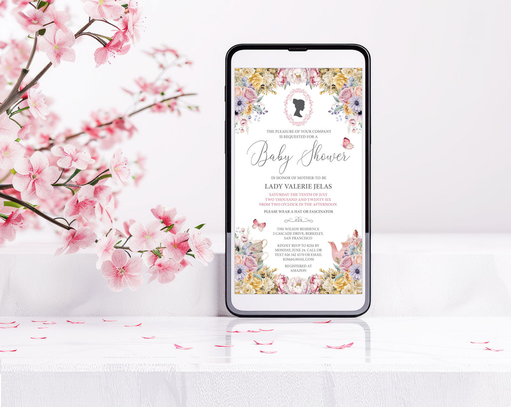 a black mobile phone with a pastel flower baby shower tea invitation showing on the screen, leaning up against a white wall with some pink blossoms
