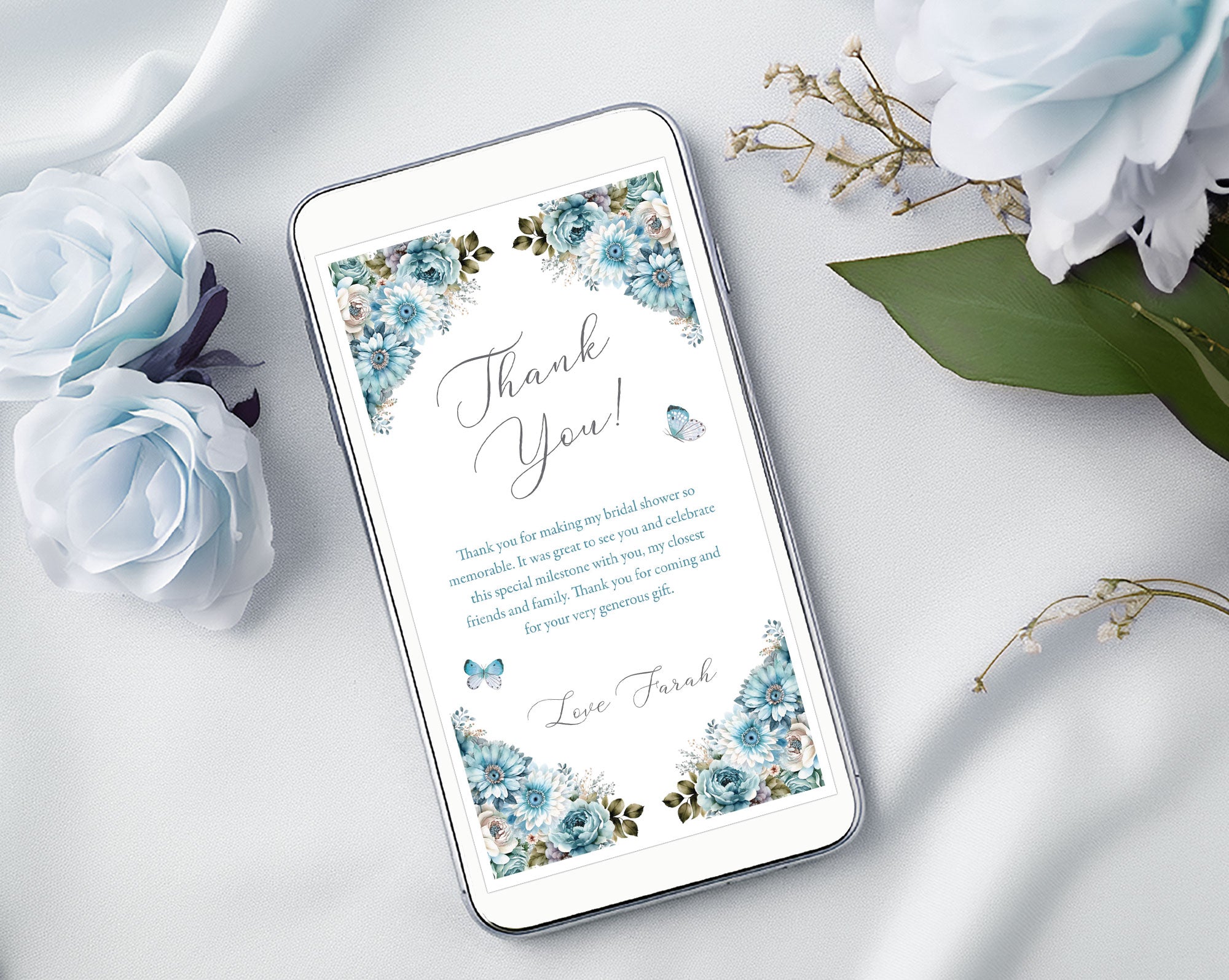 white mobile phone with a dusty blue thank you note on the screen surrounded by light blue roses on a white background