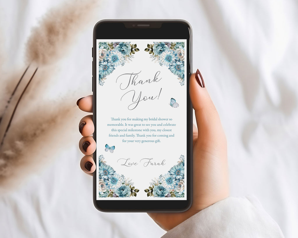 hand holding a black mobile phone over a white background with a blue flower Thank You note showing on the screen and dried flowers in the background