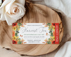 A printed event ticket for 'Urban Farm Presents a Harvest Tea' styled on a rustic wood slice with a white rose and draped fabric in the background. The ticket features a white center with elegant script text, surrounded by a colorful floral border in orange, yellow, and green, with a red vertical 'ADMIT ONE' stripe on the right.