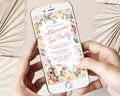 two hands holding a mobile phone showing an afternoon tea party invitation with a floral border, teapot, champagne and butterfly graphics over a white beige background