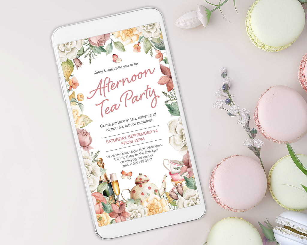 elegant floral afternoon tea invitation showing on a white mobile phone which is laying on a white background surrounded by macarons