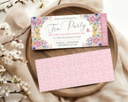 pastel Tea party event ticket with floral design on a wooden plate with flowers.
