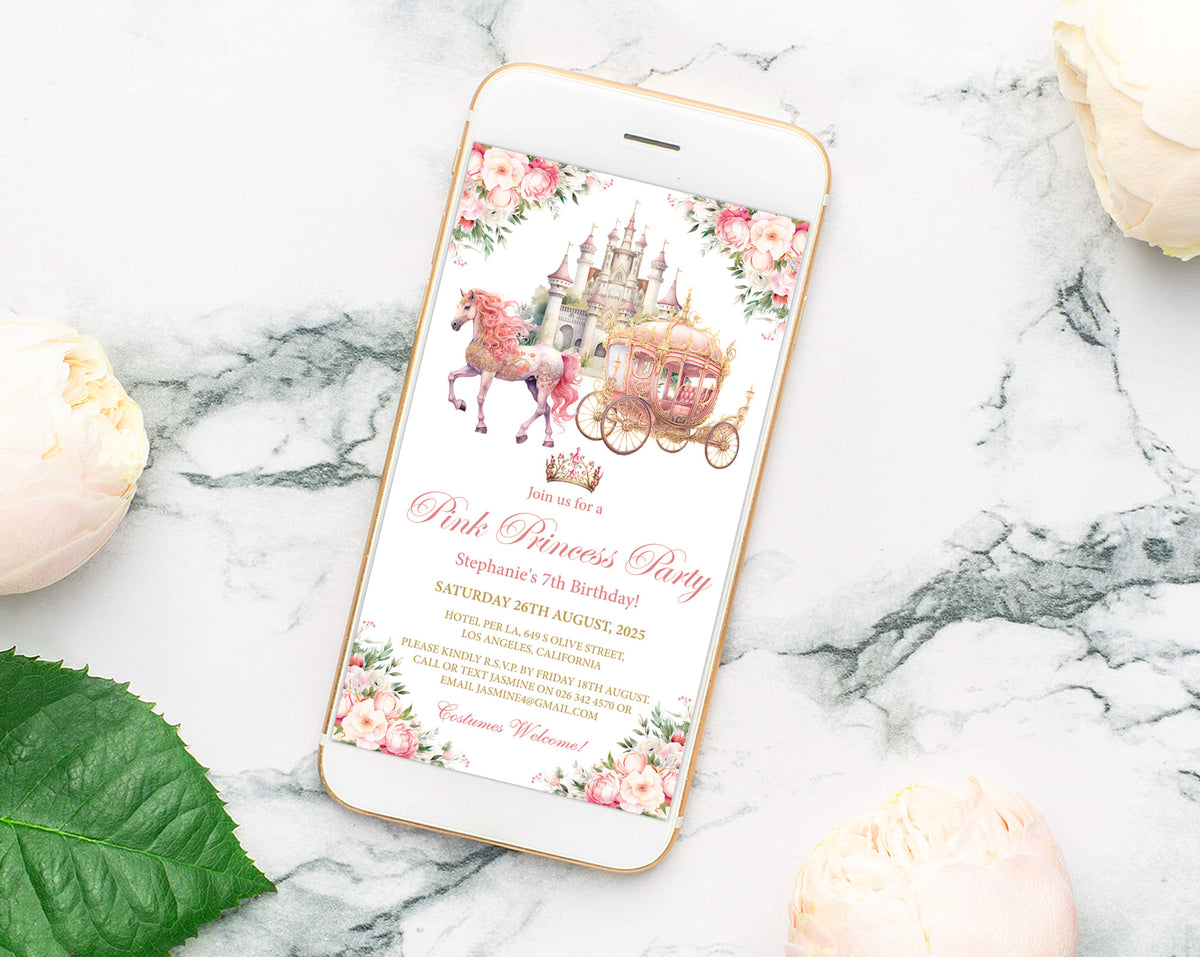 A smartphone lying on a white marble surface displays a pink princess party invitation design with a castle, unicorn, carriage, and floral border. The phone is styled with pale pink flowers and a green leaf around it.