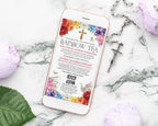 A smartphone lying on a white marble surface, displaying a colorful church fundraiser invitation titled 'Rainbow Tea.' The phone is surrounded by purple flowers, a green leaf, and a silver cross.