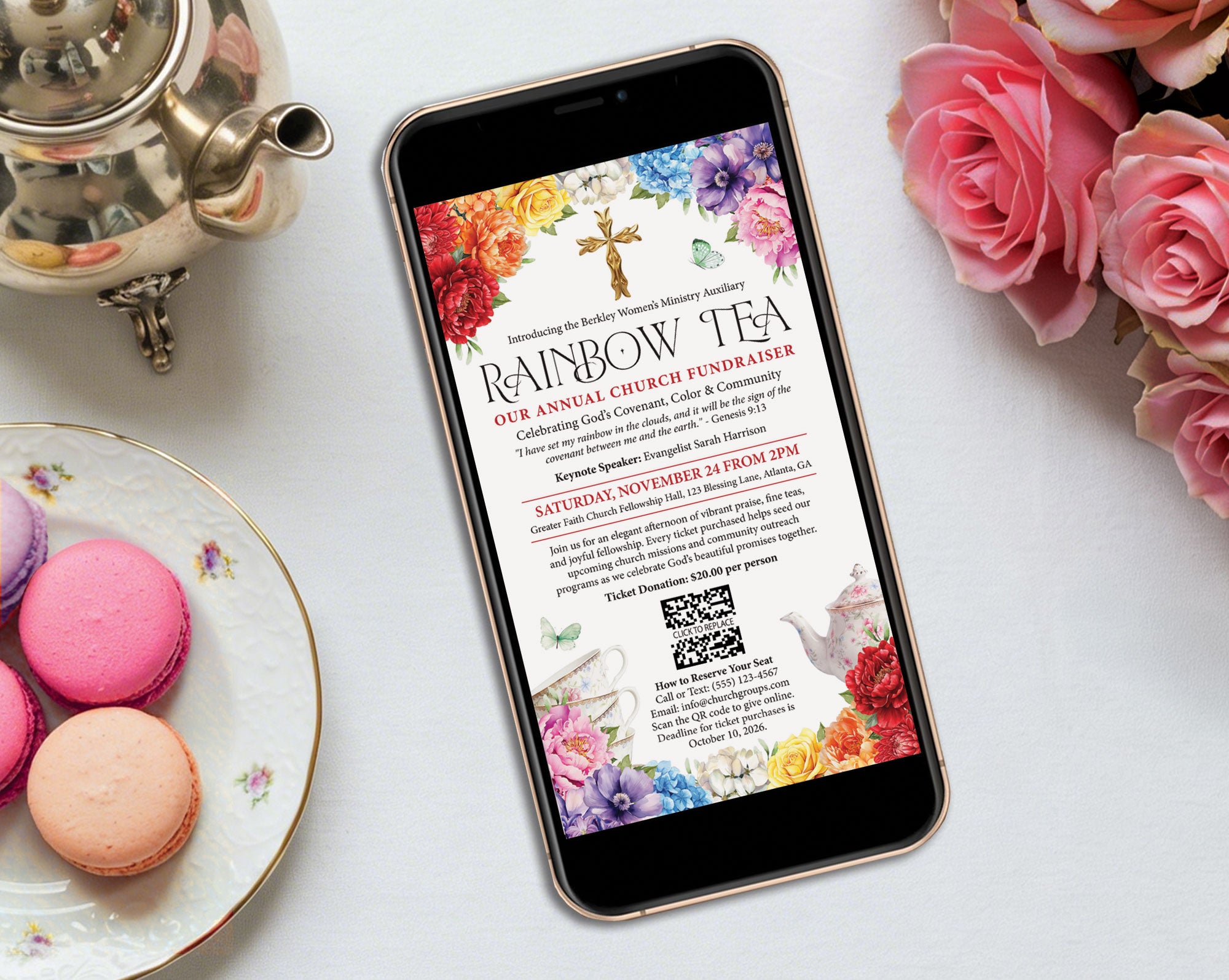 A smartphone lying on a white surface, displaying a colorful invitation for a church fundraiser titled 'Rainbow Tea.' The scene is styled with pink macarons on a plate, a silver teapot, and pink roses around it.