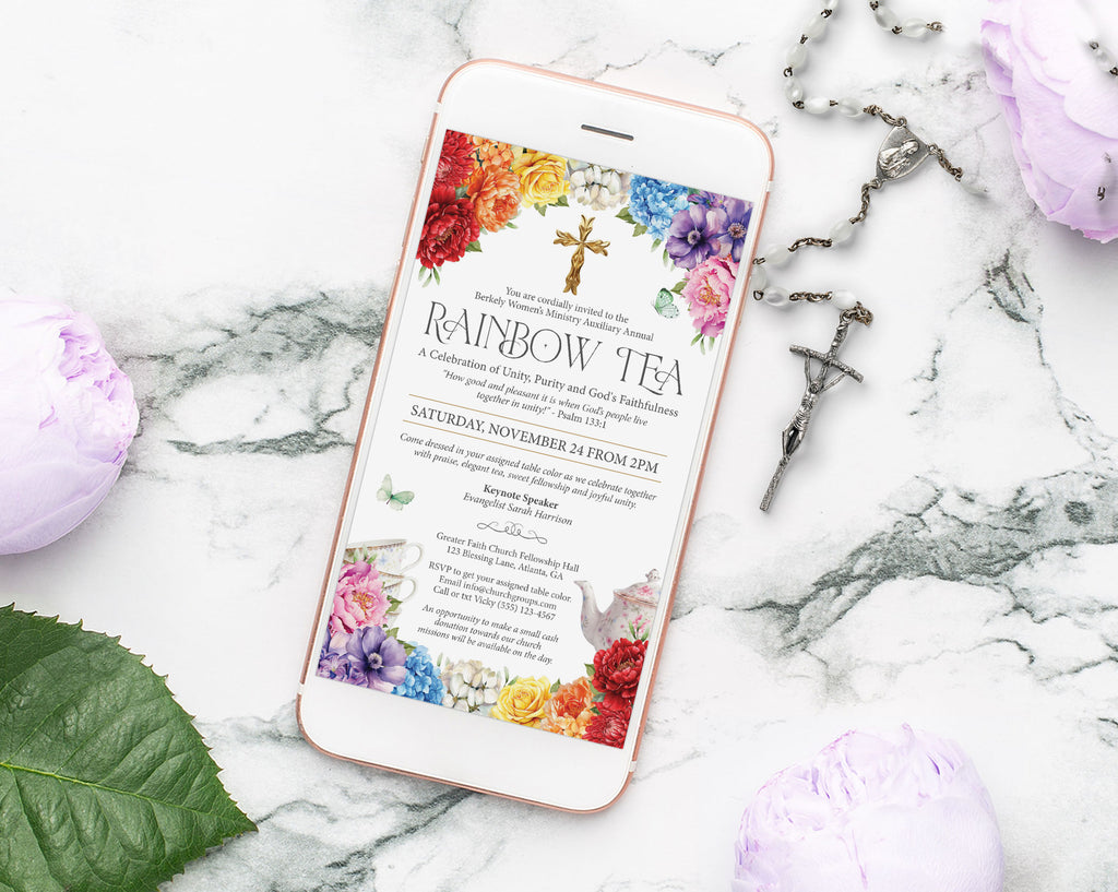 a white mobile phone with a colorful rainbow event invitation laying on a marble surface with a crucifix and some lilac flowers next to it