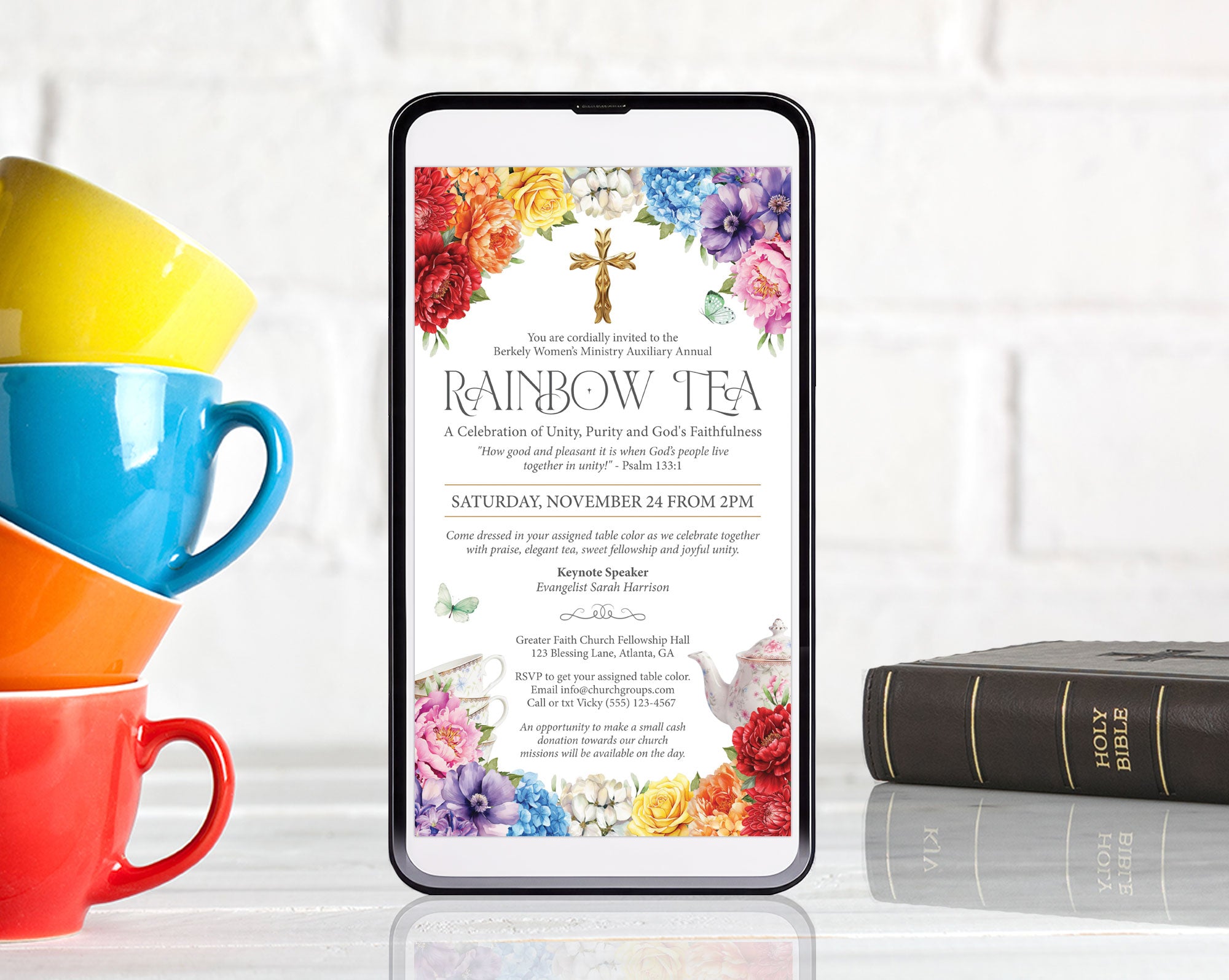 4 bright stacked cups next to a black mobile phone with a rainbow tea church event invitation showing on the screen and a bible on the right hand side