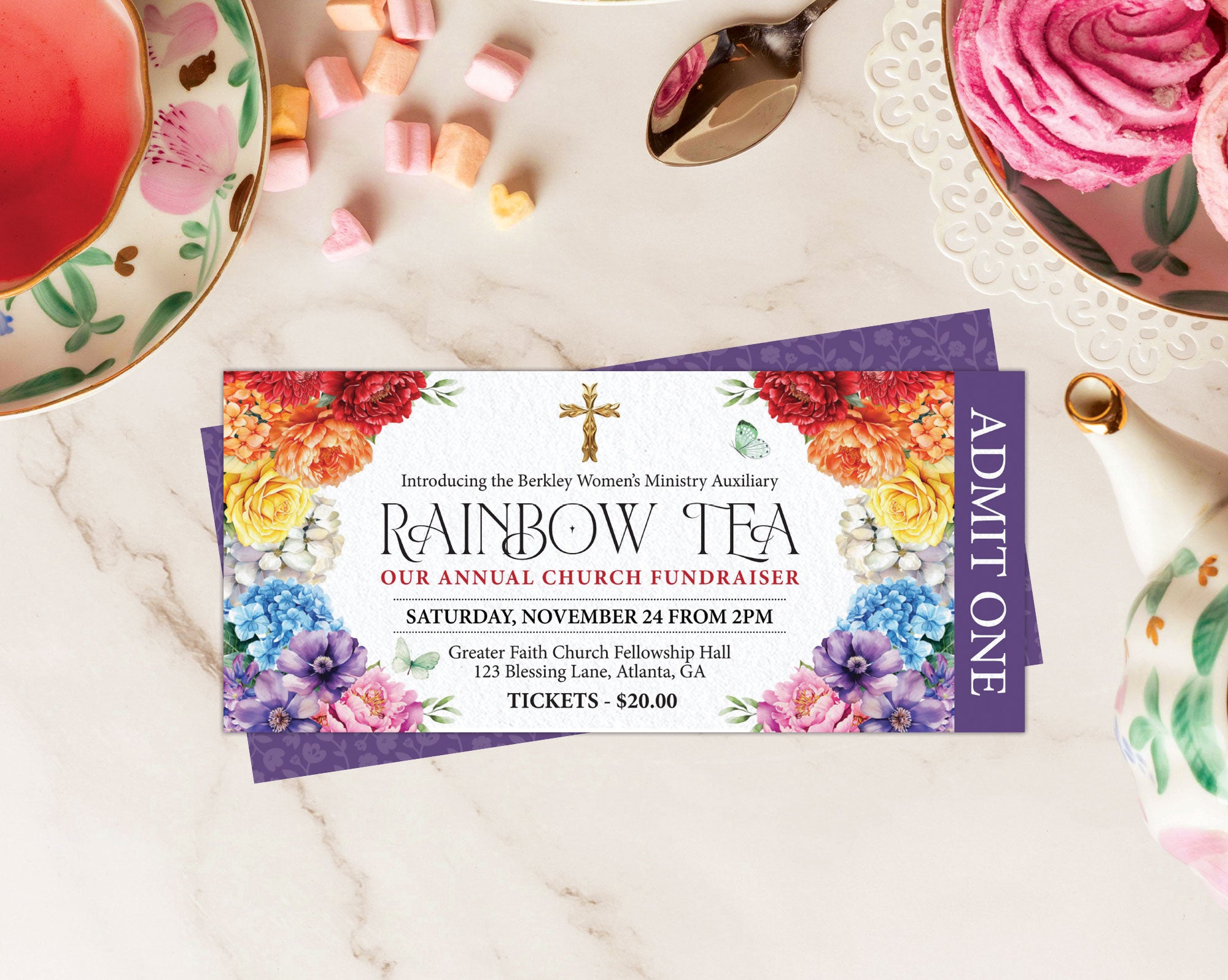 two rainbow tea admit one tickets for a church event, 1 showing the front and 1 showing the back laying on a beige table top with pink meringues and tea set