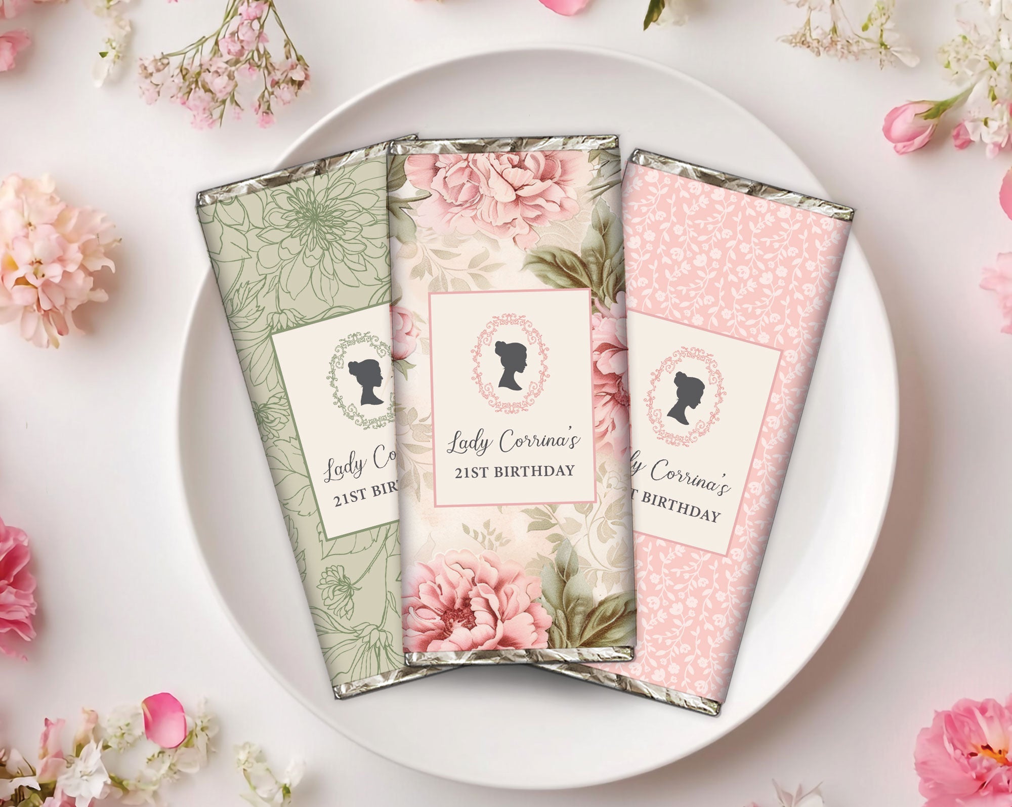 Three pretty 21st birthday Regency floral-themed chocolate bars on a white plate with pink flowers in the background