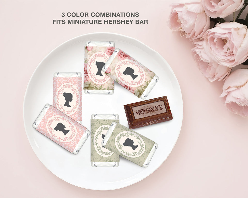 Miniature Hershey bars with decorative bridgerton inspired wrappers on a white plate, surrounded by pink roses