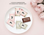 Miniature Hershey bars with decorative bridgerton inspired wrappers on a white plate, surrounded by pink roses