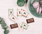 Hershey's chocolate bars with decorative victorian style wraps on a wooden surface with a plate of macarons