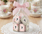 pretty favor bag with mini regency style cameo chocolates tied with a pink bow on a lace doily with floral teacups in the background