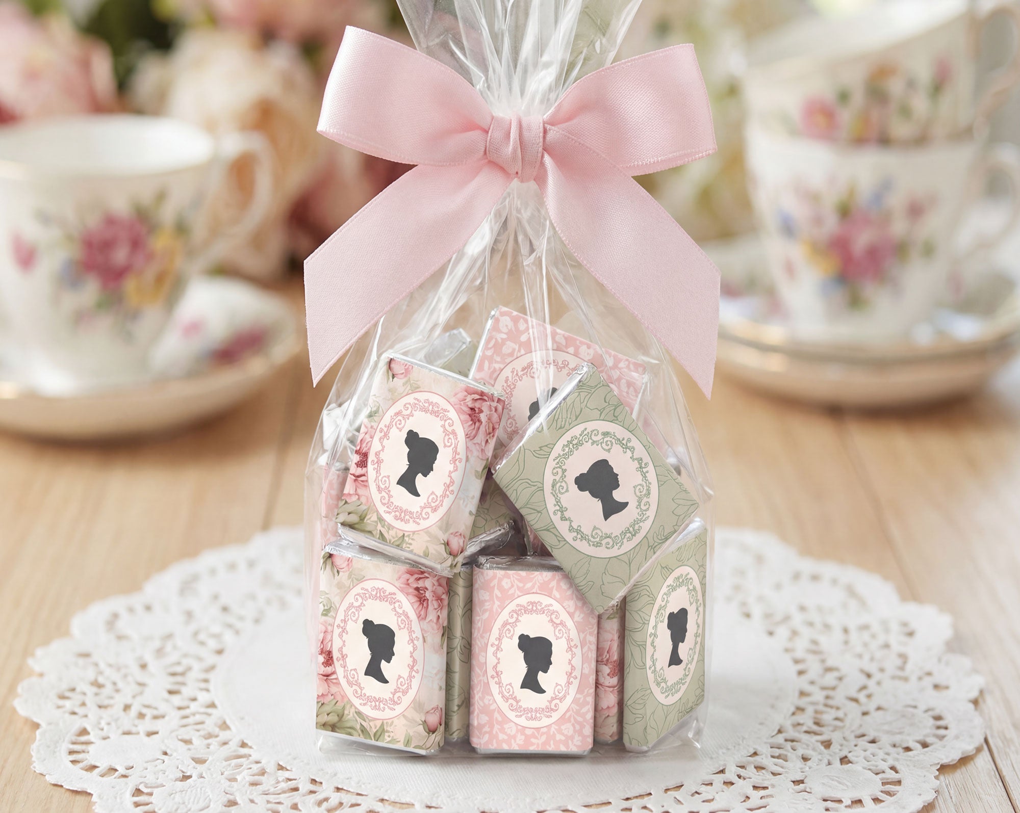 pretty favor bag with mini regency style cameo chocolates tied with a pink bow on a lace doily with floral teacups in the background
