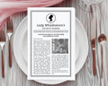 A printed vintage-style paper titled "Lady Whistledown's Society Papers" with Afro American cameo is laid flat on a white plate, surrounded by silverware and a pink napkin on a gray wood surface.