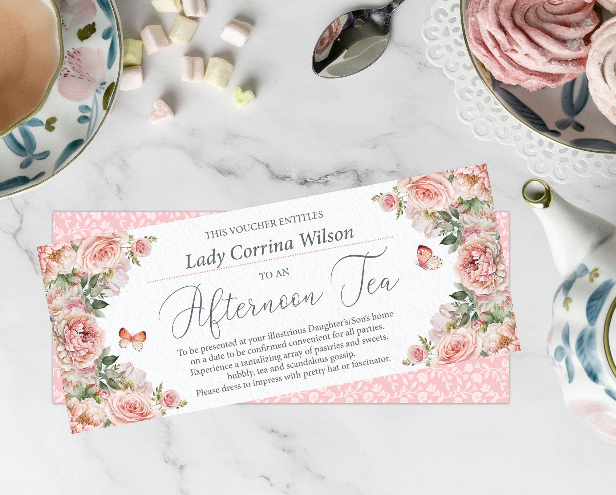 Gift voucher for an afternoon tea with floral design on a marble surface with tea set items.