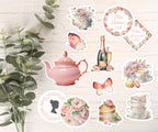 Collection of decorative stickers or cake toppers featuring teapots, flowers, and other elements on a wooden surface.