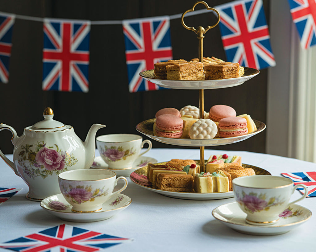 Tea set with cakes and macarons on a table with British bunting in the background
