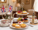 British lifestyle pic with Tea set with cakes, fruit, and a cake shaped like Big Ben in a formal dining setting.