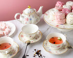 Tea set with floral teapot and cups on a marble surface with pink background